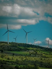 White Wind Turbines on Green Grass Field Under Blue Sky