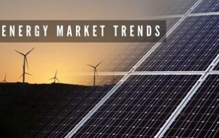 A picture of a sunset behind several windmill silhouettes on a horizon. On the right side is a transparent picture of a dark blue and white solar panel. On the top left is a brown graphic rectangle with the words, “ENERGY MARKET TRENDS.”