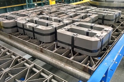 A close-up angle of a metal factory belt, with several tightly wound gray transformer cores, shaped in a way that resembles a square number eight.