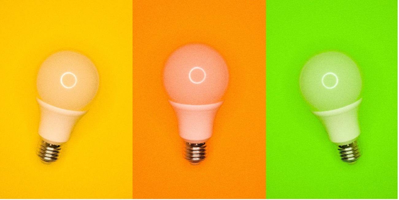 Three LED bulbs with yellow, orange, and light green as each of their backgrounds.