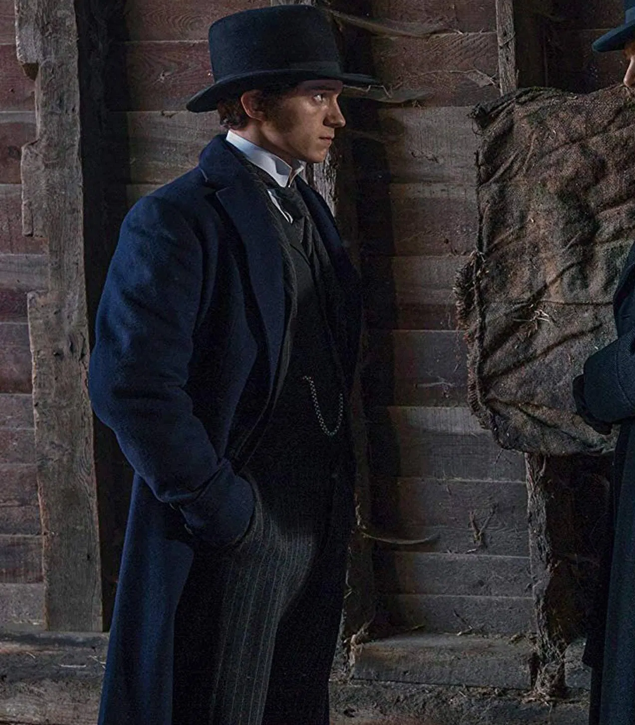 Actor Tom Holland as Samuel Insull in the movie The Current War; he is dressed in 1920s period costume: a top hat, a three-piece suit, a navy frock, and a pocket watch.