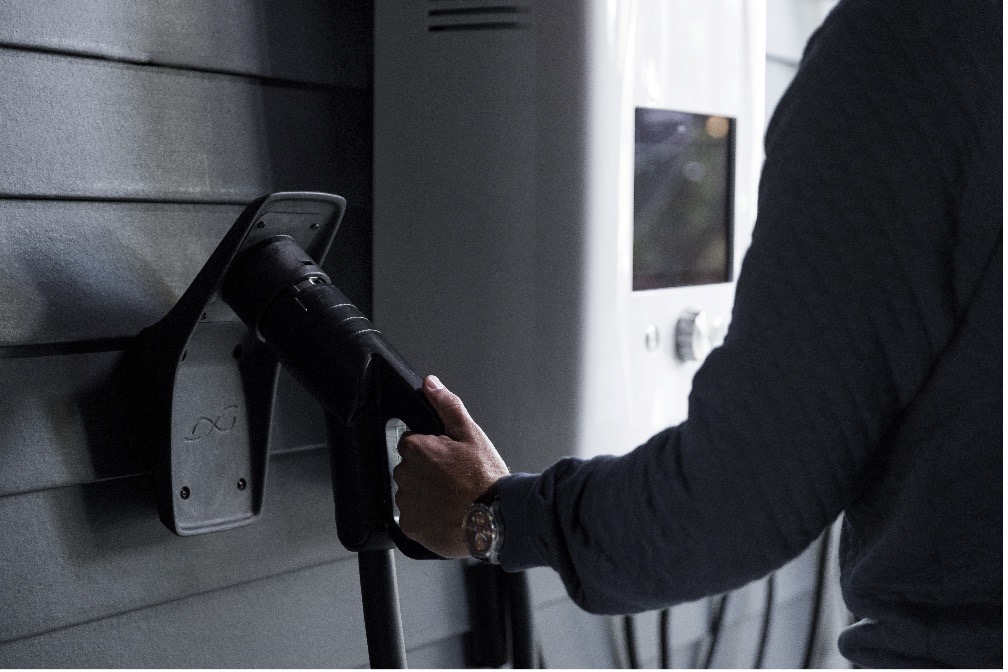 A home EV charging connector hooked to the wall of a garage.